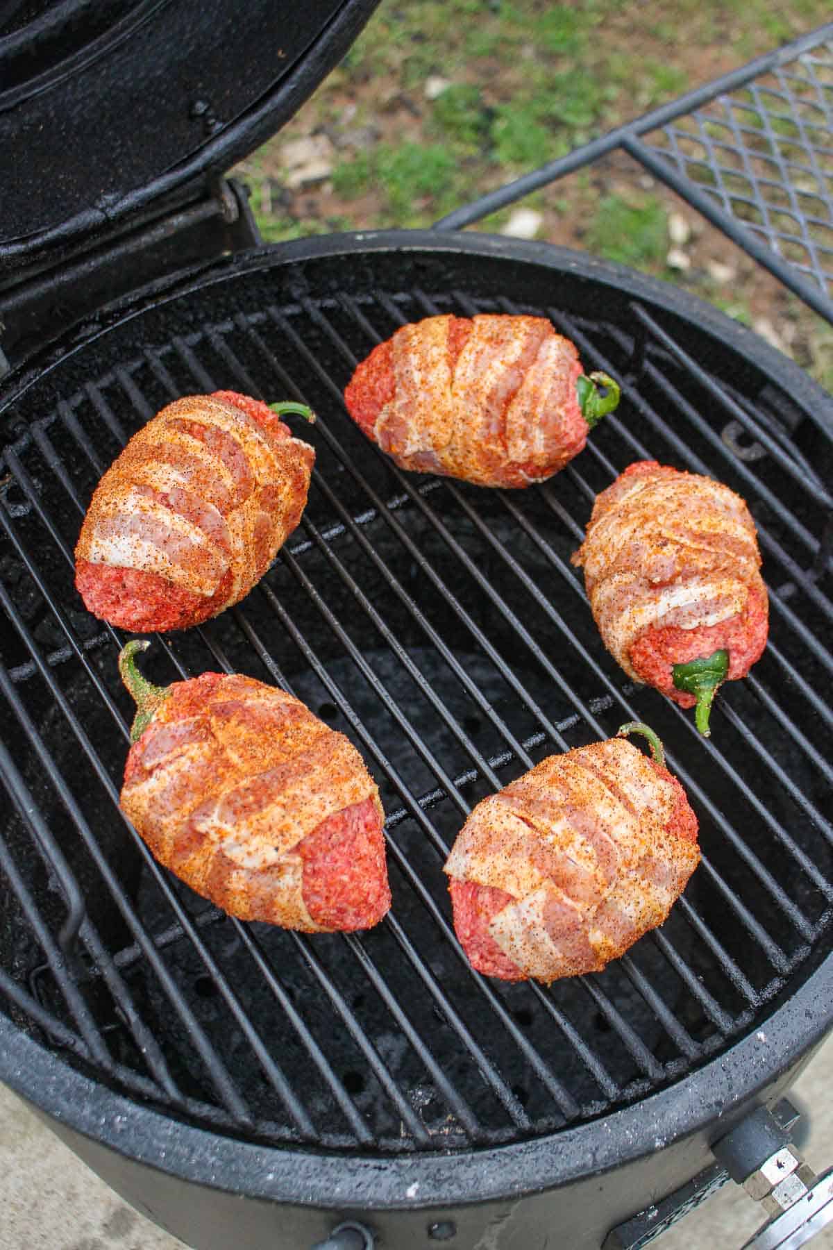 The seasoned and raw beef armadillo eggs placed on the smoker.
