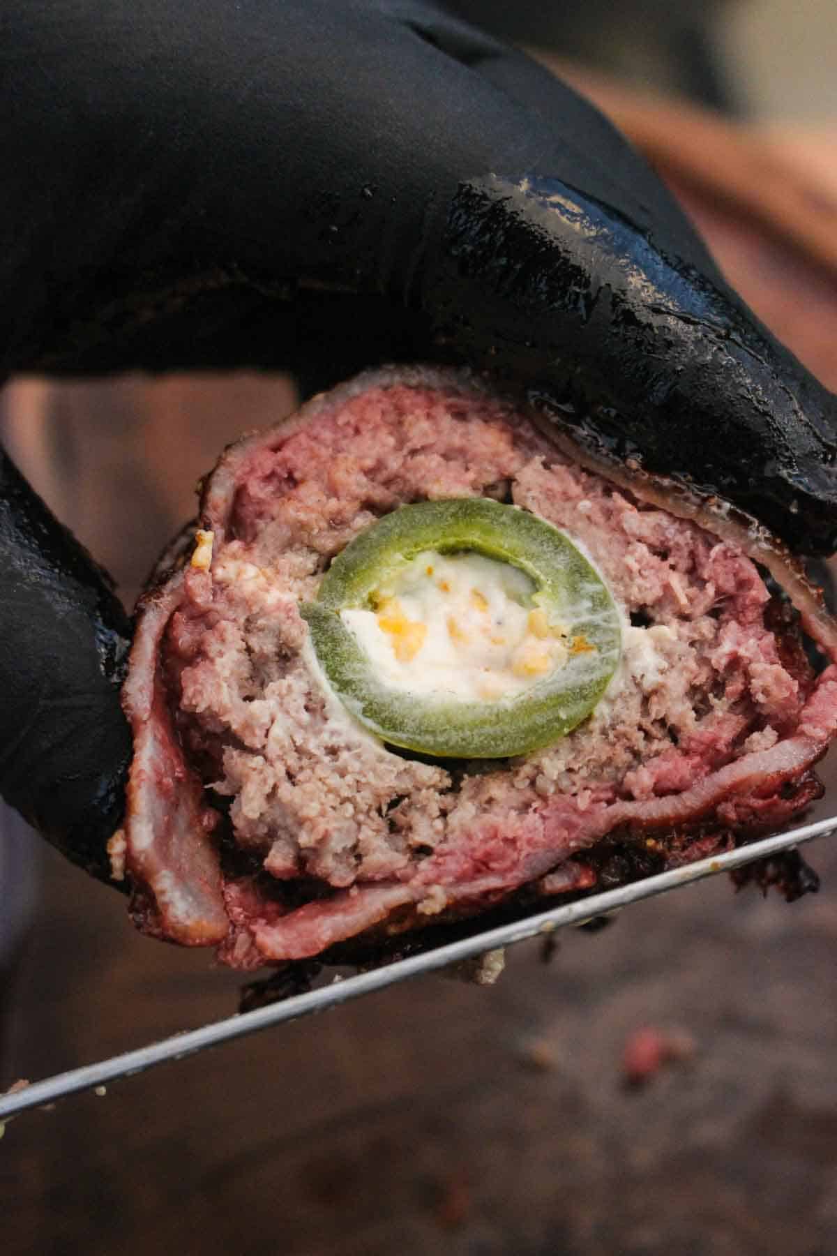 A sliced beef armadillo egg held up for the camera.
