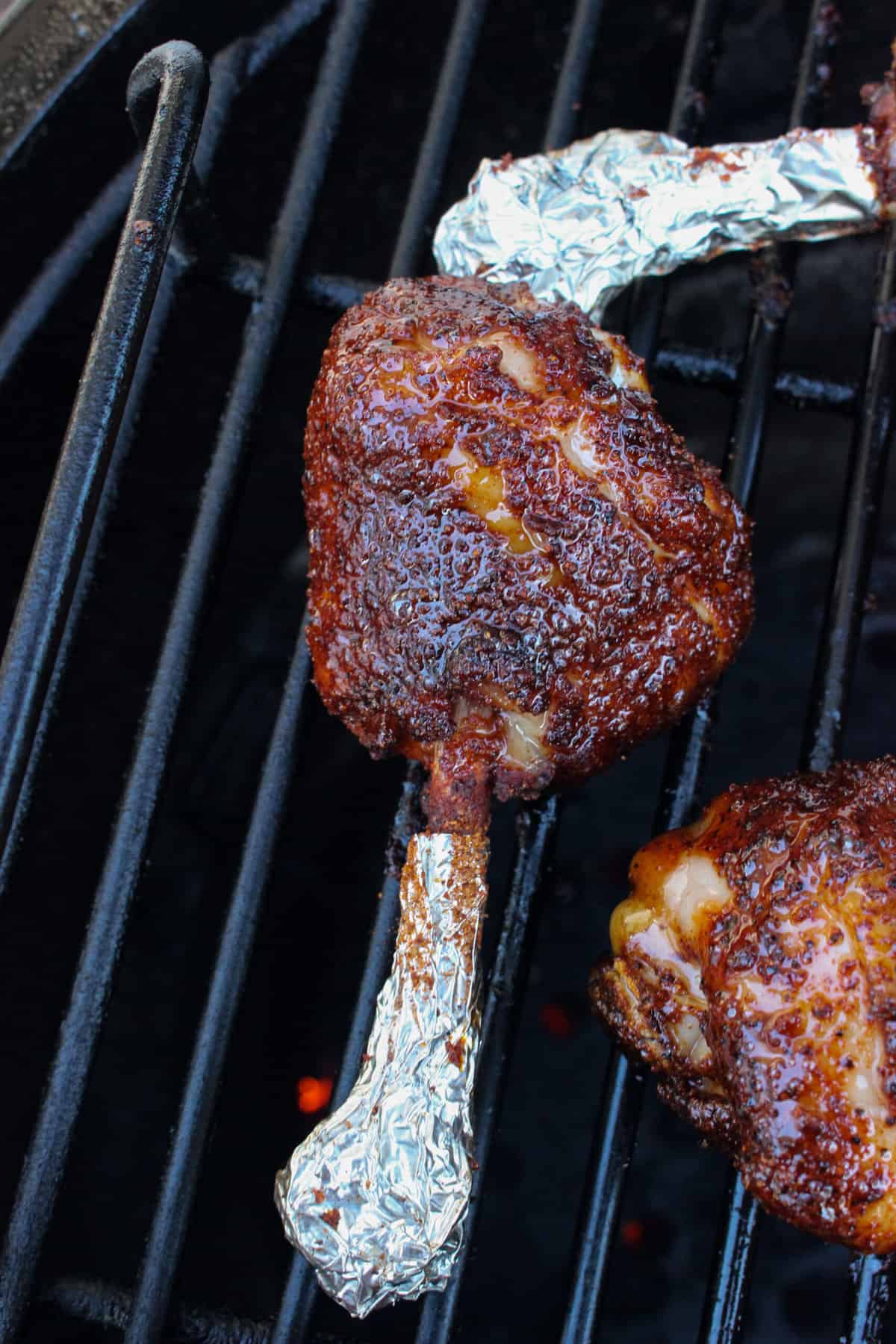 A close up shot of a glazed drumstick almost finished cooking on the smoker.