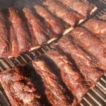 The beef ribs smoking on the grill.