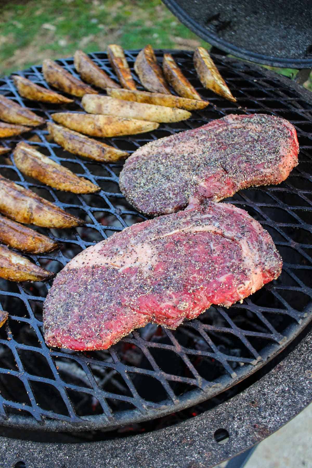 The two ribeye steaks sitting on the grill next to the wedges.