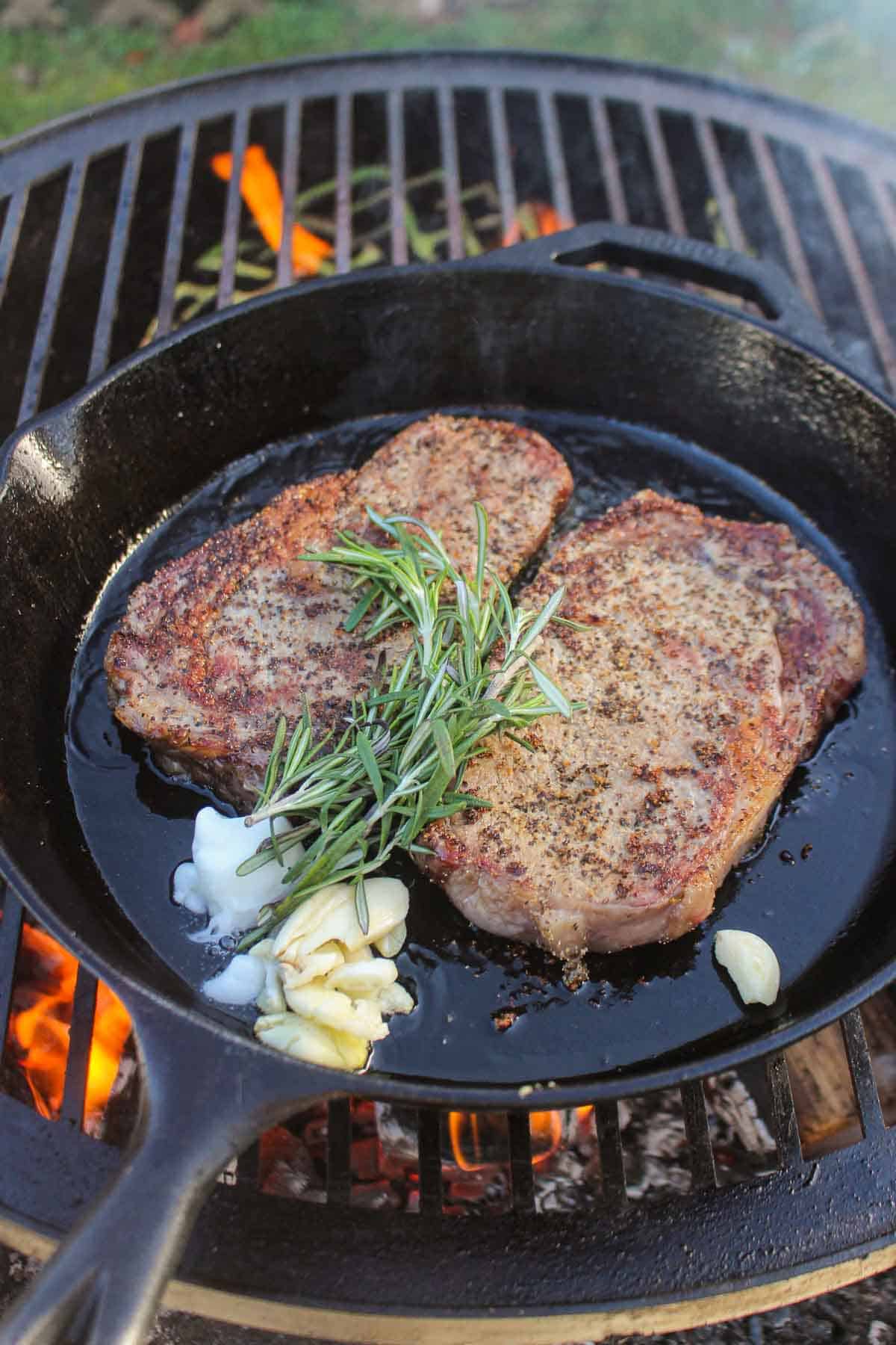 Cooking the steaks in a skillet with rosemary, garlic and beef tallow.