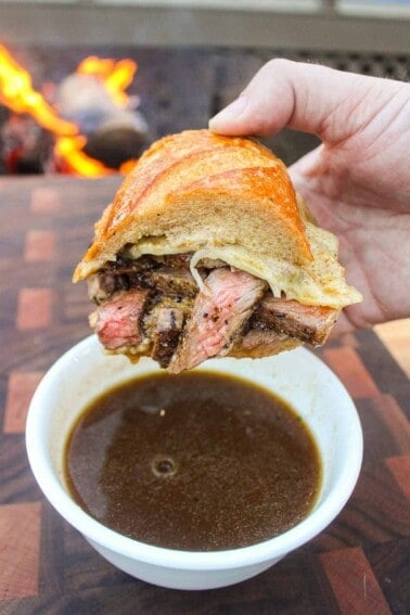 A photo of the sandwich being dipped in the au jus.