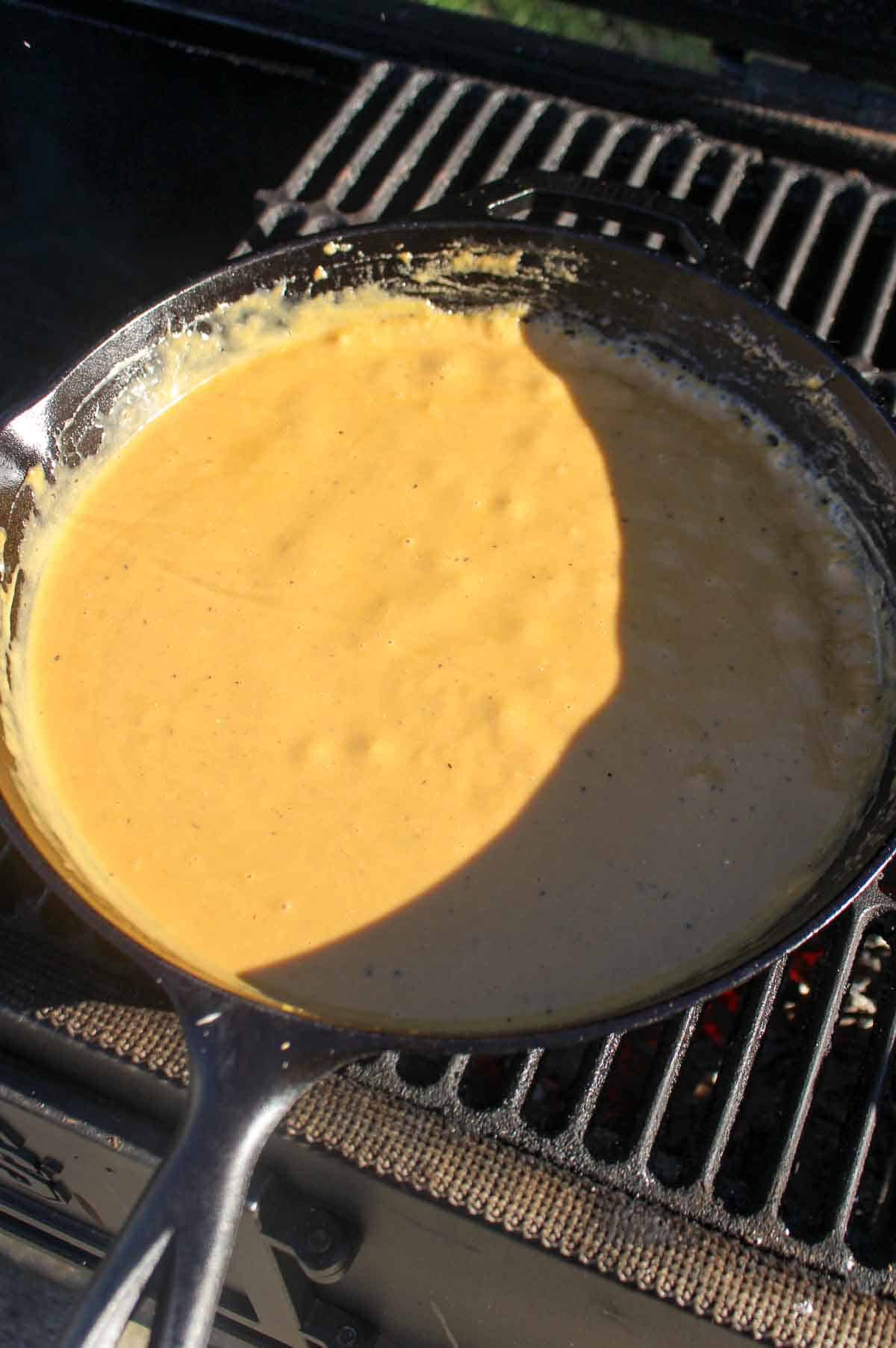 The finished cheese sauce bubbling over the fire.