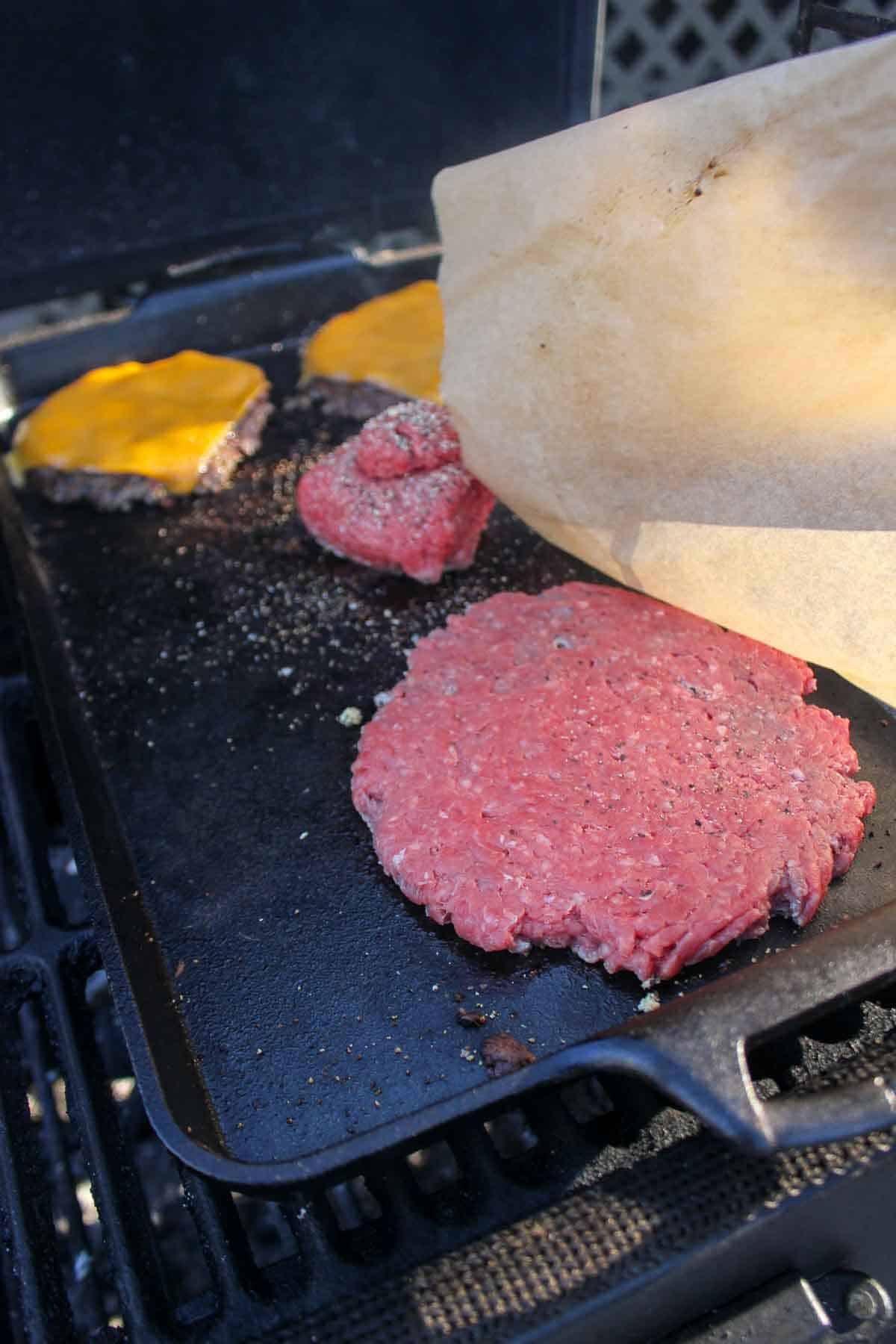 Smashing the burger patties to form the smash burgers.