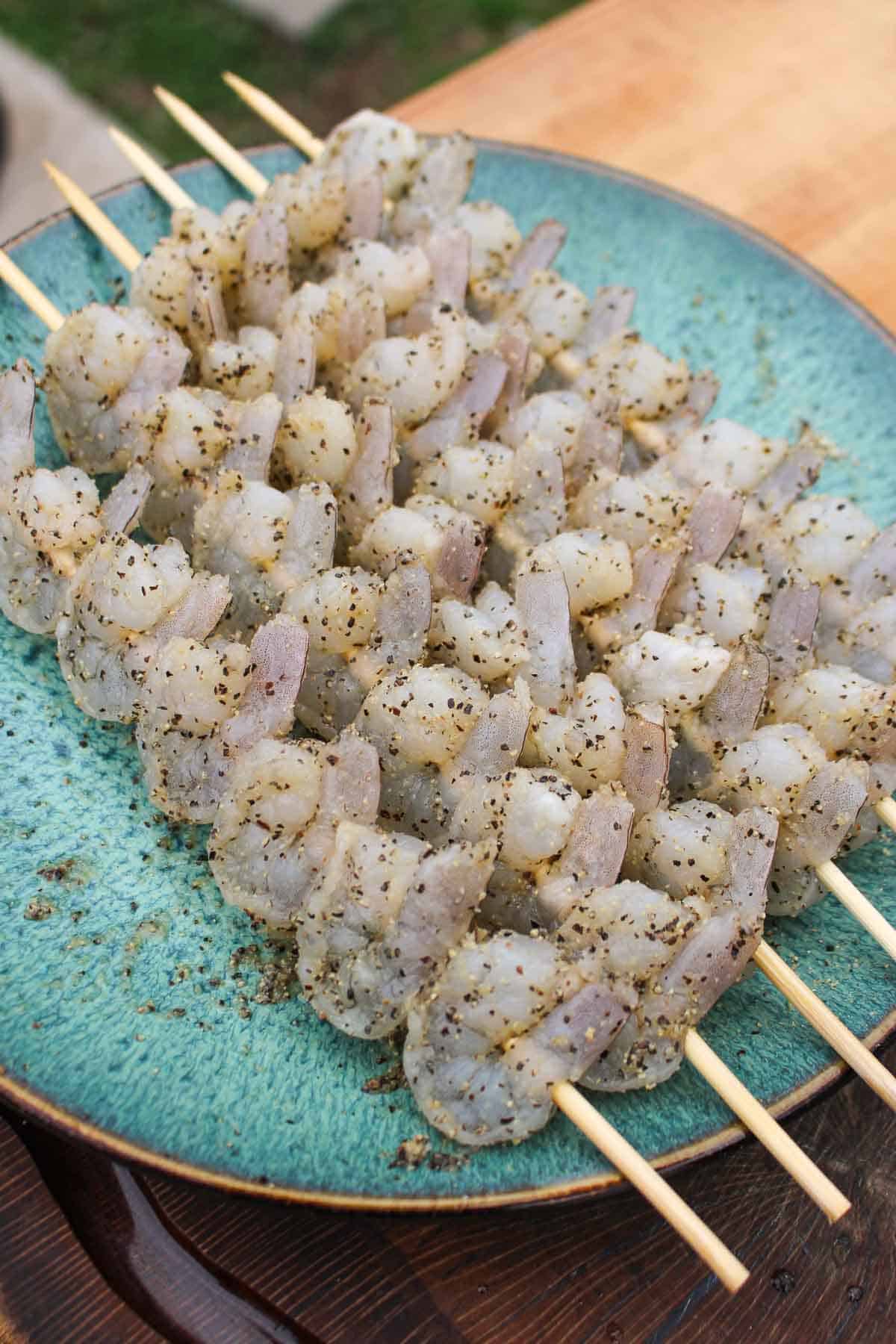 The raw shrimp placed on the wooden skewers.
