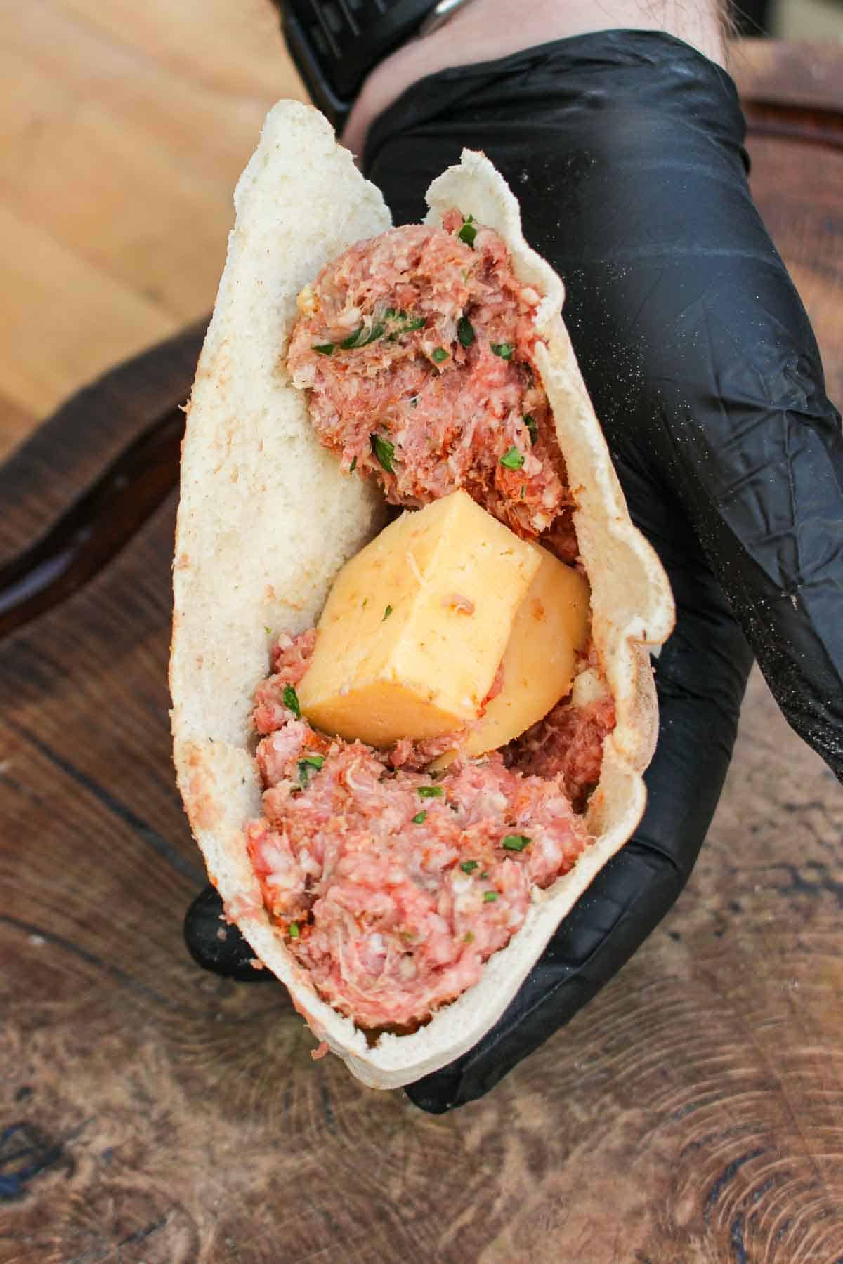 Stuffing the pita pocket with lamb and cheese.