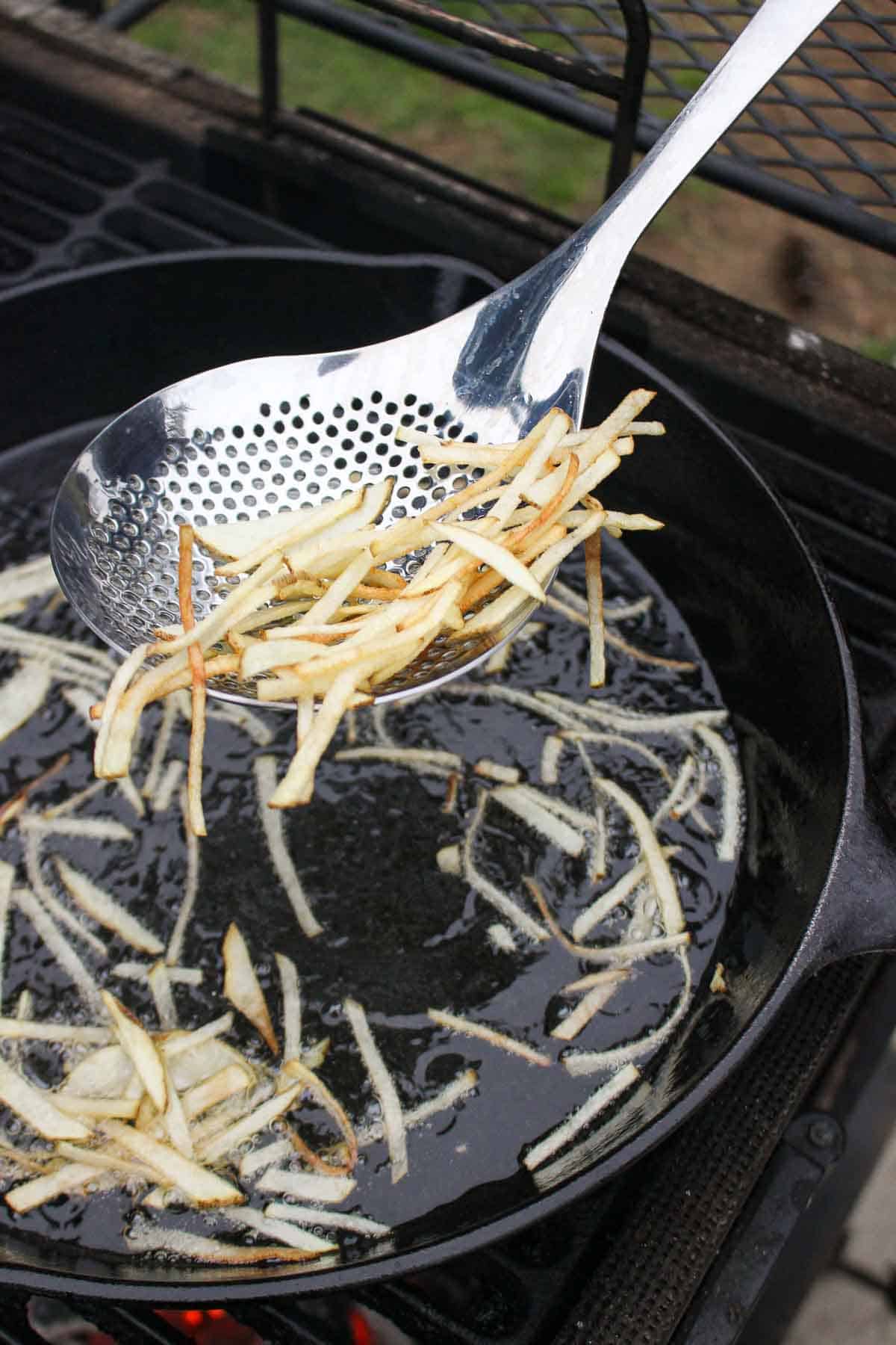 Pulling the French fries out of the frying oil.