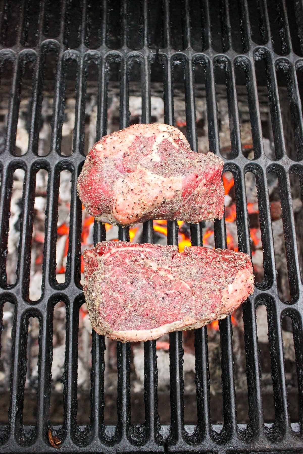 The raw steaks set on the grill so that they can start cooking.
