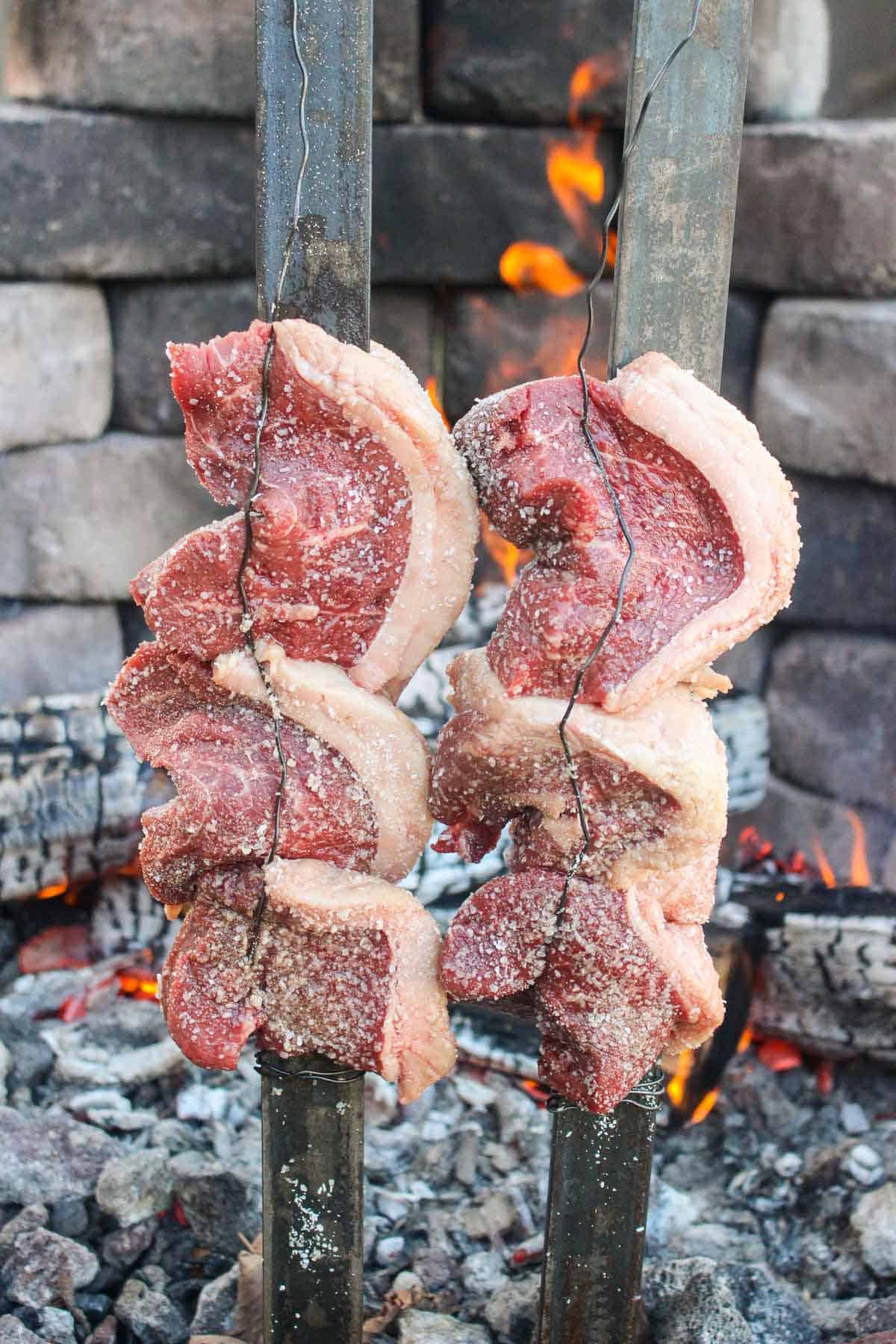 Skewered picanha cooking by the fire.