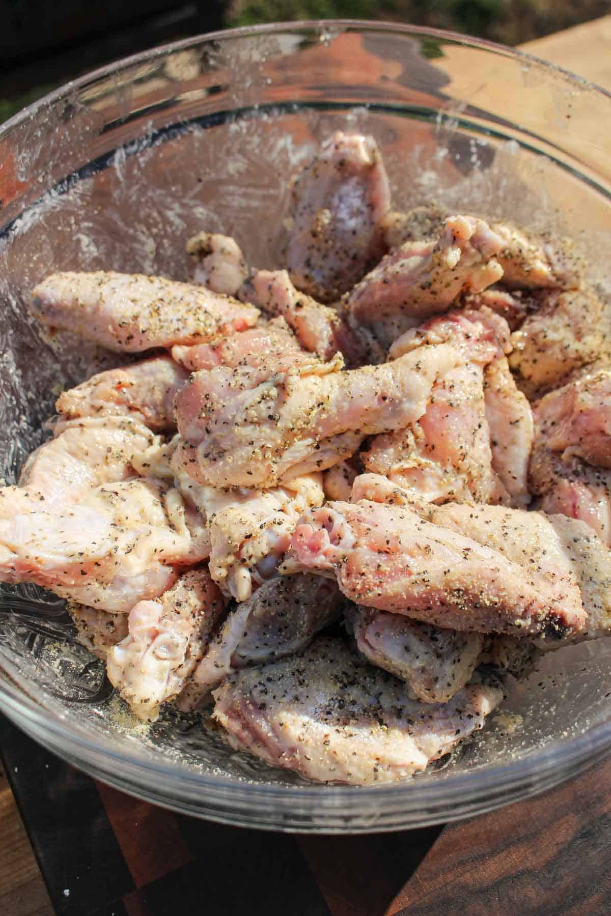 The seasoned, raw chicken wings in a bowl.