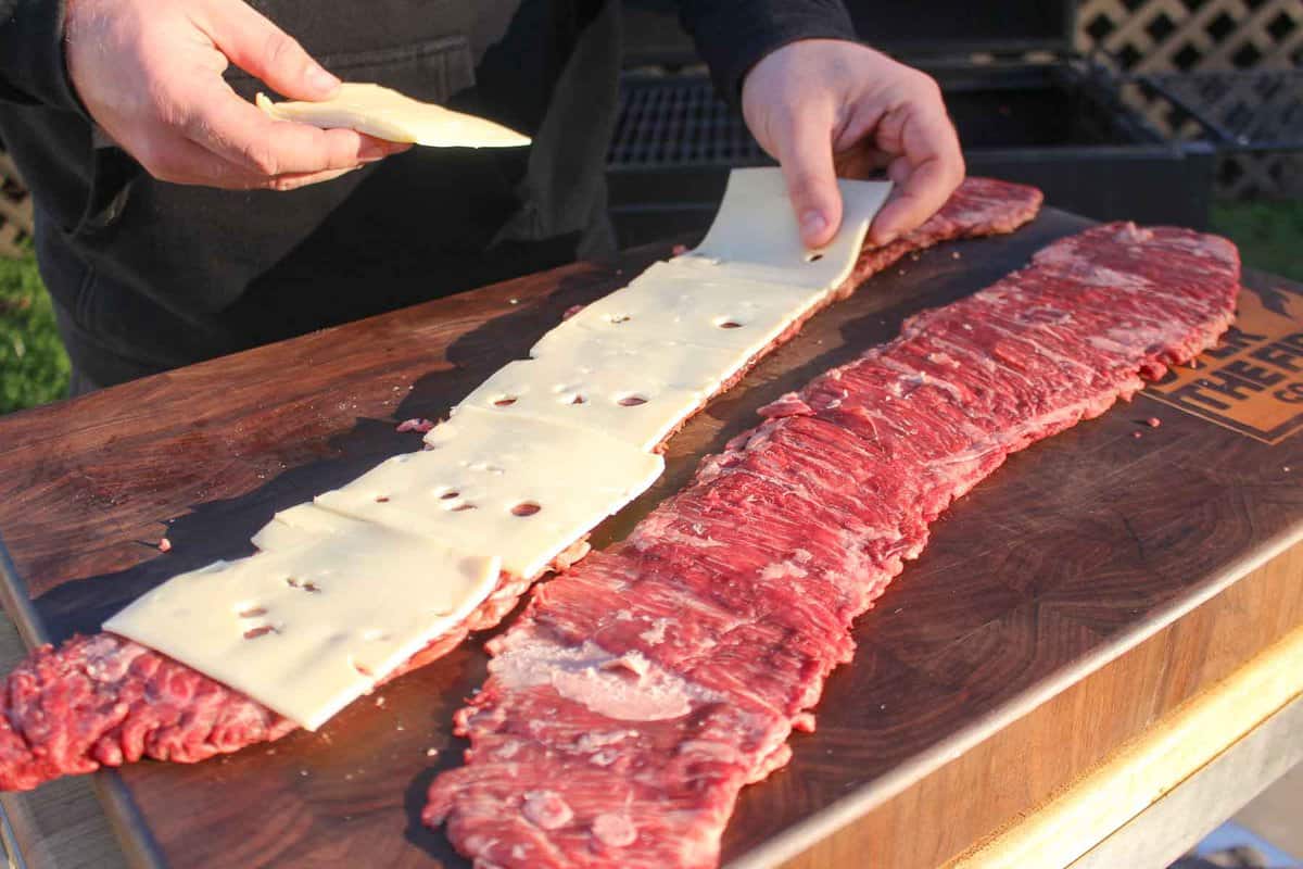 Adding a layer of cheese  to the skirt steaks.