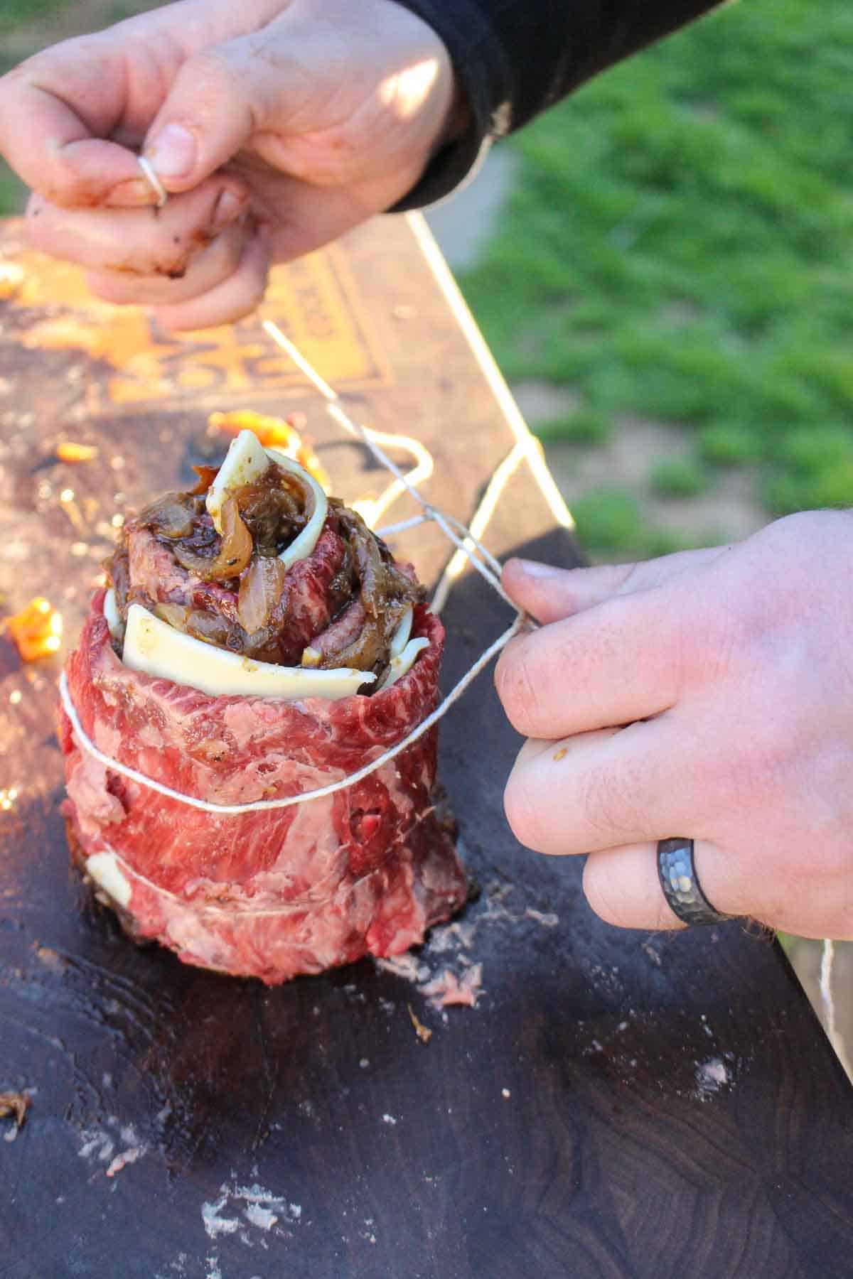 Tying up the French Onion Steak Pinwheels with the twine so that they stay together while cooking.