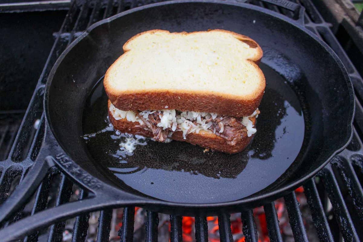 Adding the Birria Grilled Cheese Sandwich to the skillet.