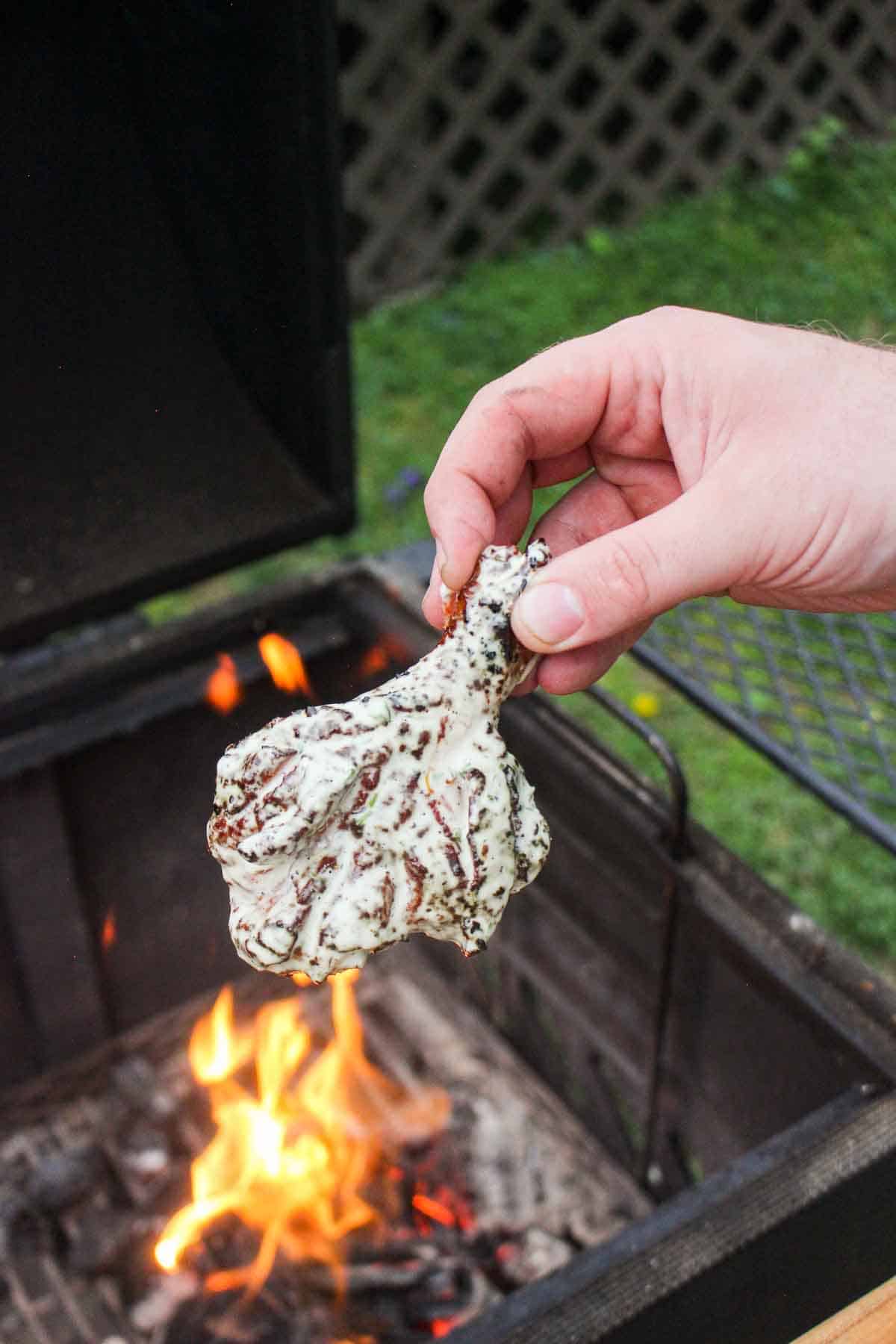 One of the dipped wings being held next to the fire.