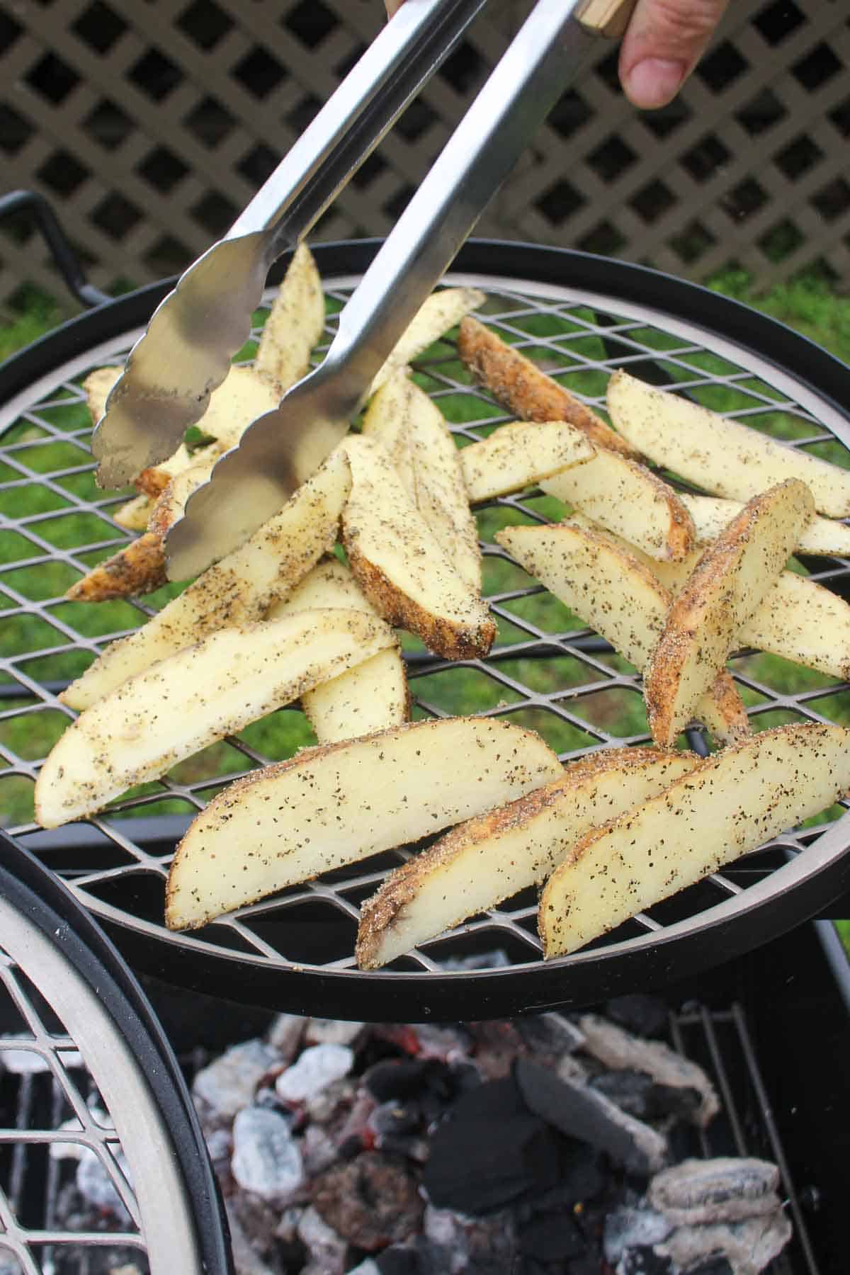 Spacing the potato wedges out evenly on the grill grate.