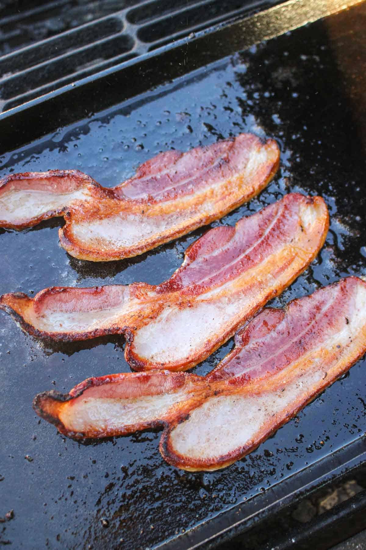 Cooking the bacon on the skillet.