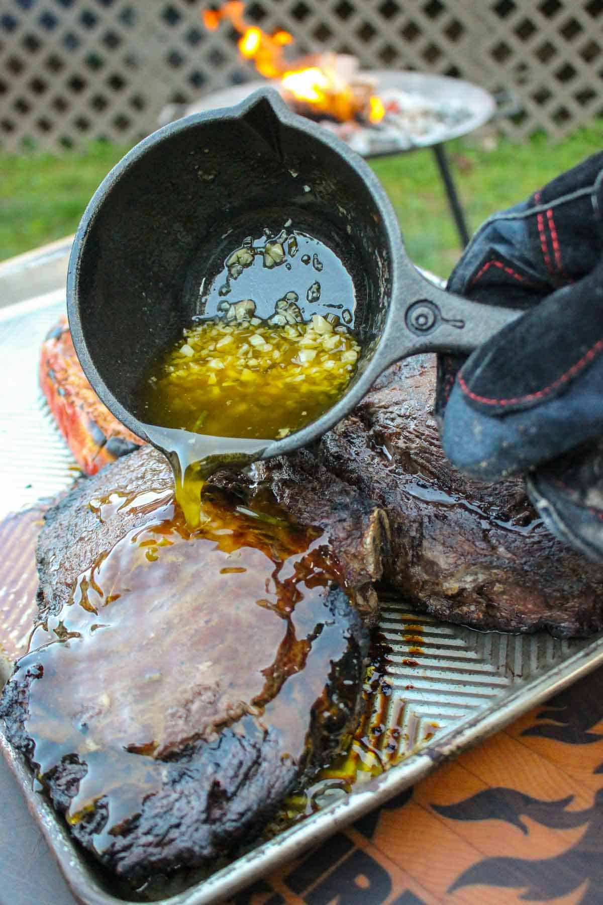 Pouring the butter sauce on top of the tomahawks.