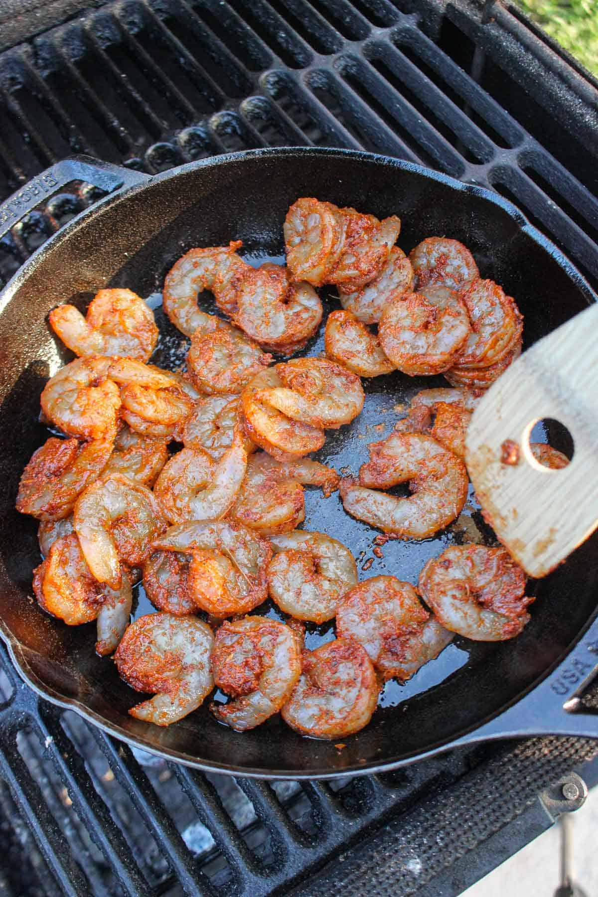 Adding the raw shrimp to there skillet for the surf and turf sandwich.