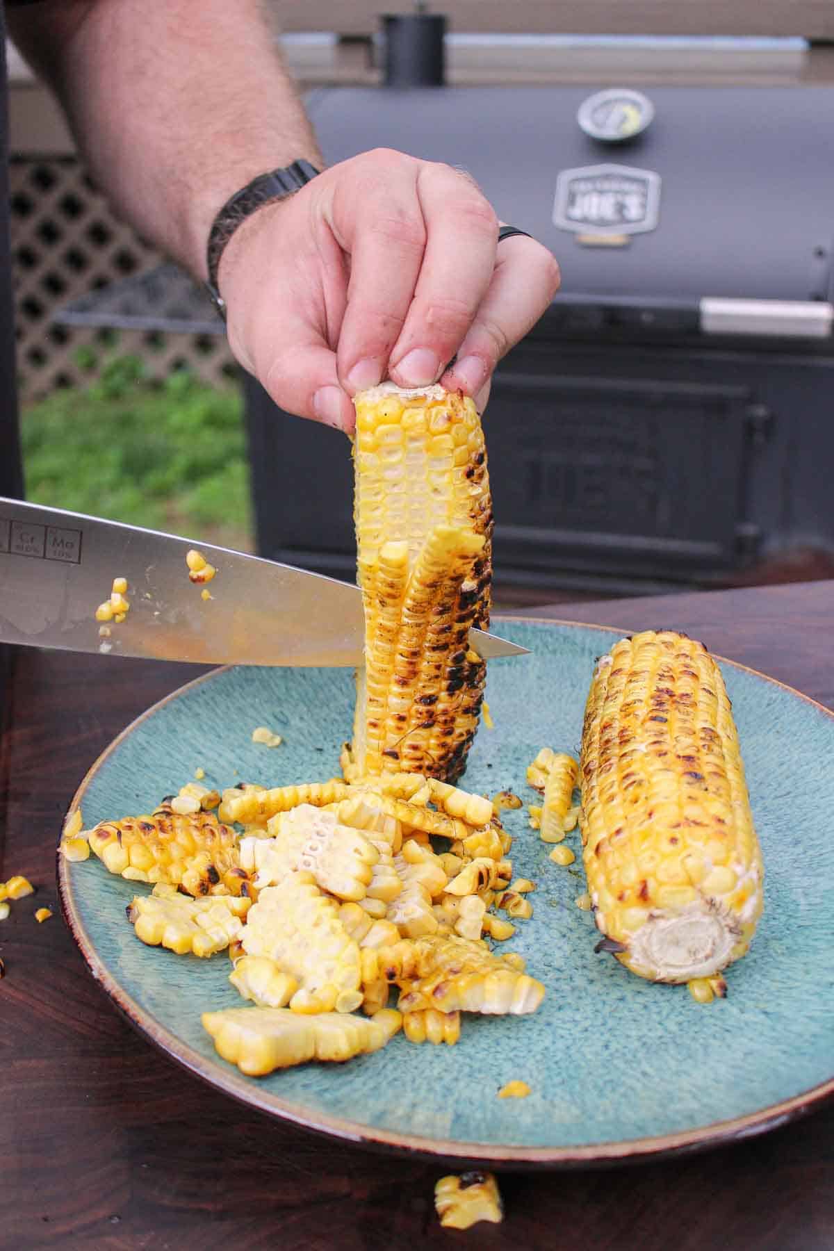 Cutting the grilled corn off the cob so that we can assemble the corn salsa.