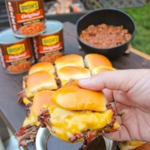 The pulled beef sliders with steakhouse baked beans sitting all together on a cutting board so that we can serve the dish.