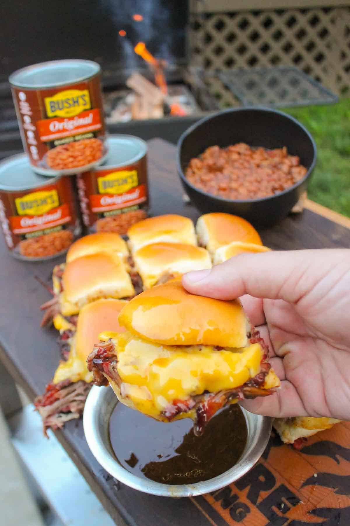 The pulled beef sliders with steakhouse baked beans sitting all together on a cutting board so that we can serve the dish.