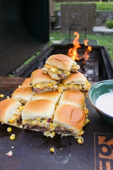 Grilled Steak Elote Sliders served on a cutting board and next to the chipotle lime mayo.