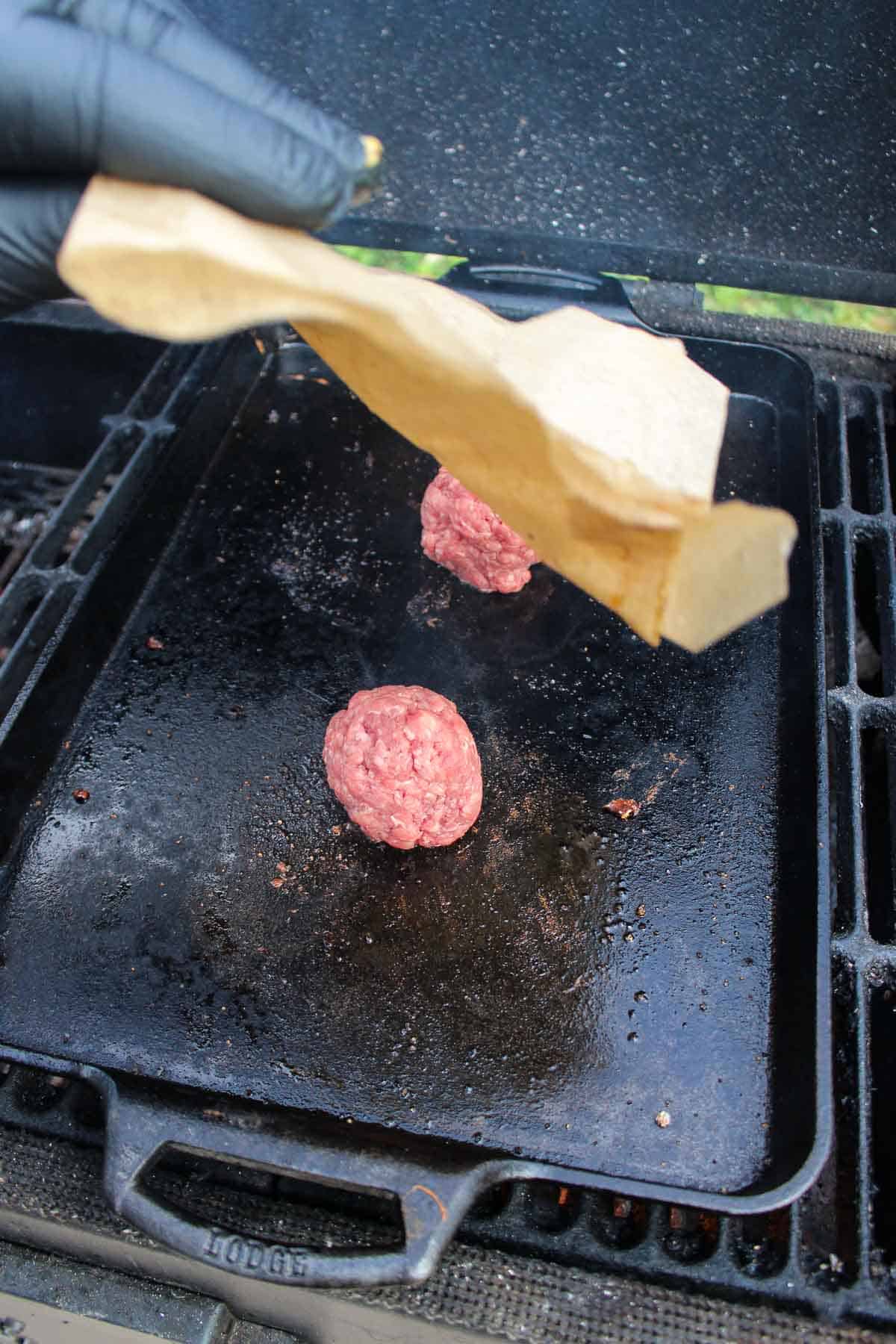 Placing the parchment paper over the burger balls so that we can smash them.