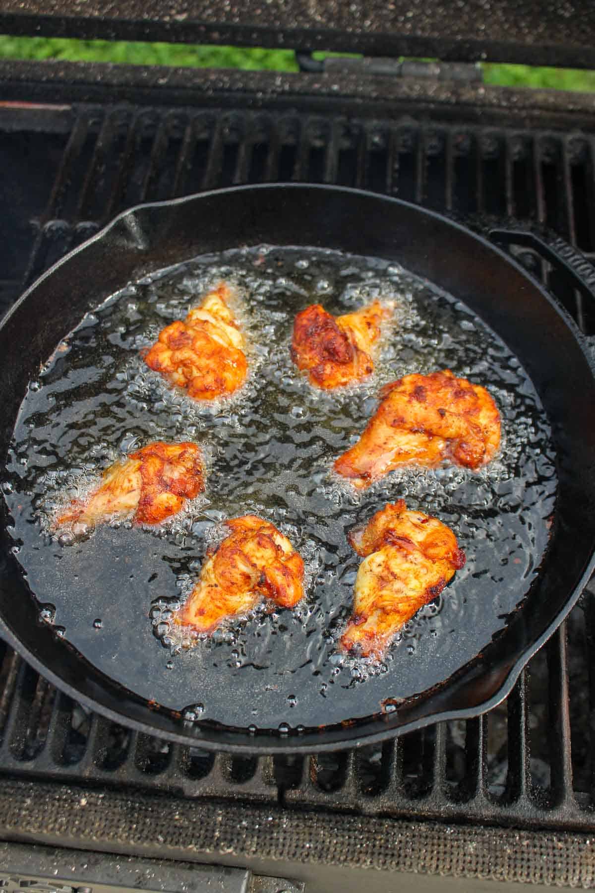 A batch of the smoked wings frying on the grill.