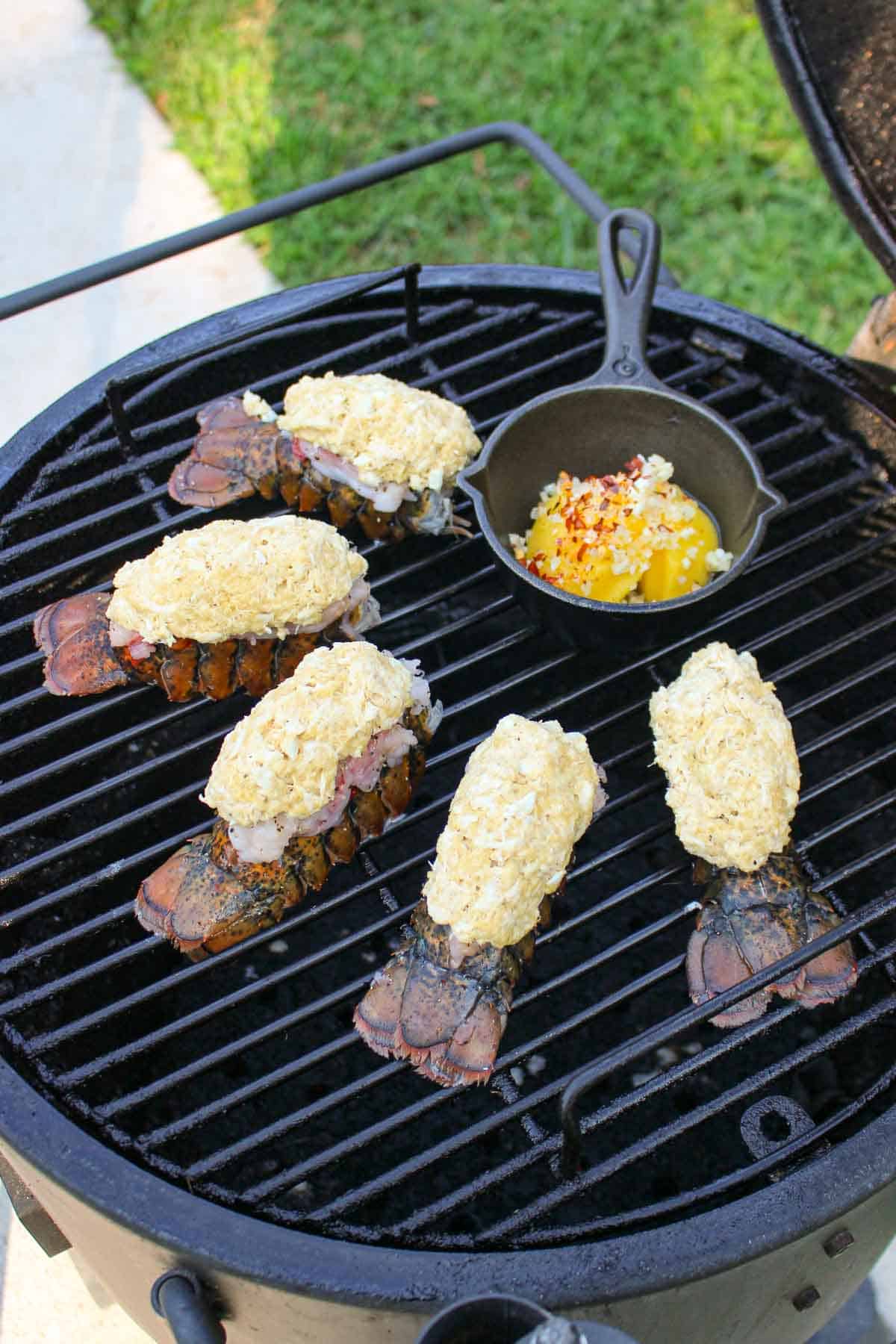 The raw crab stuffed lobster tails sitting on the grill. 