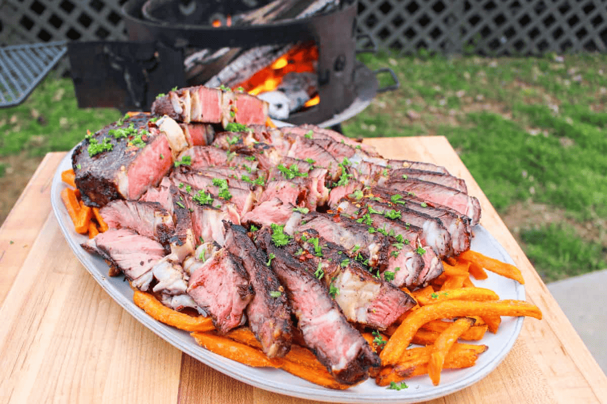 Sliced steaks sitting on a bed of sweet potato fries. 