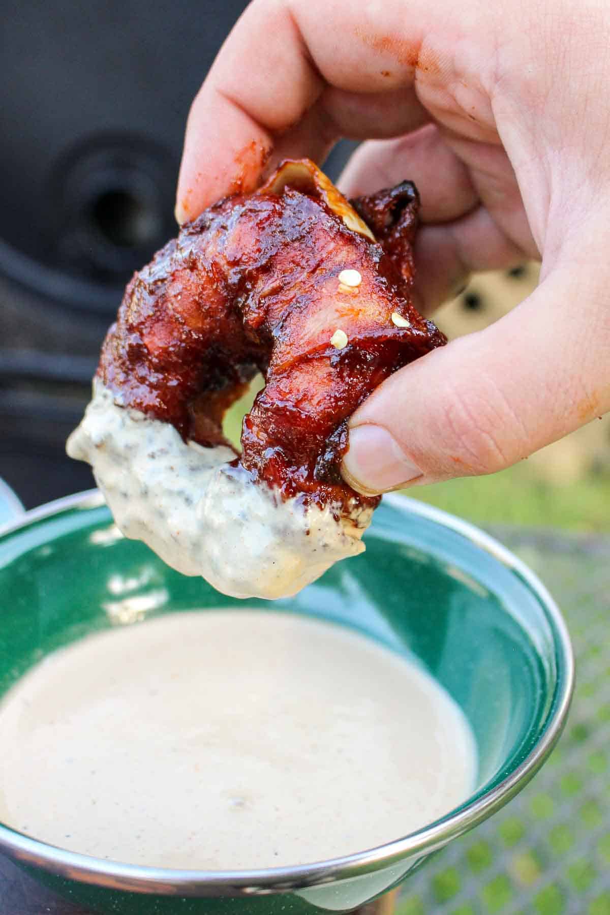 Burger Stuffed Onion Rings getting dipped in a white sauce.