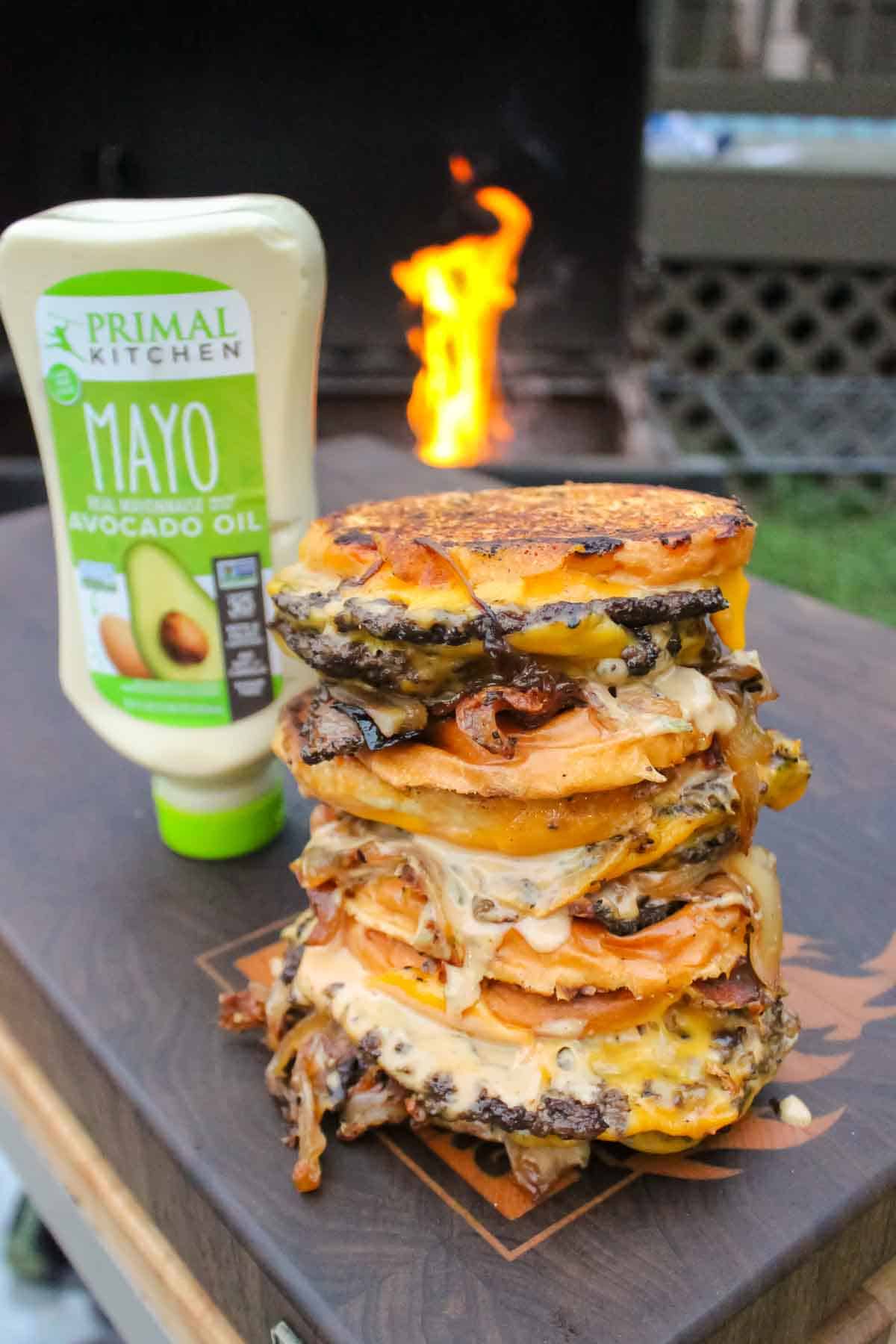 The Animal Style Patty Melts stacked on top of each other and sitting in front of the Primal Kitchen Mayo.
