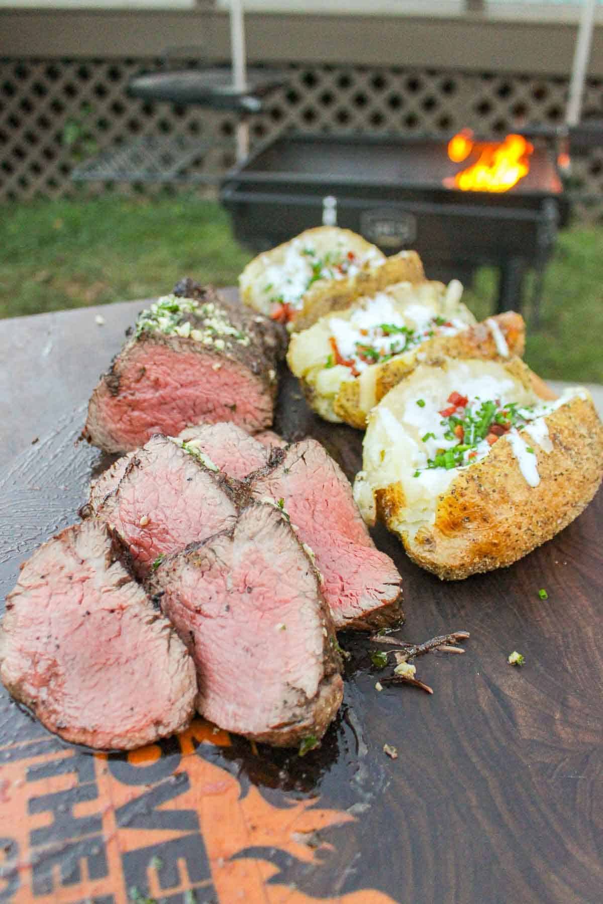 The tenderloin is sliced and presented next to the baked potatoes stuffed with all the best toppings. 