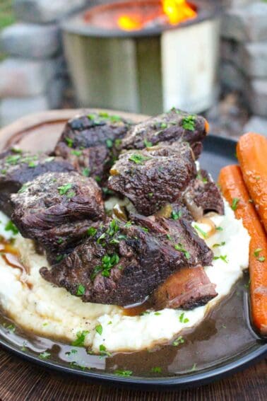 The braised beef ribs over mashed potatoes with a side of whole cooked carrots.