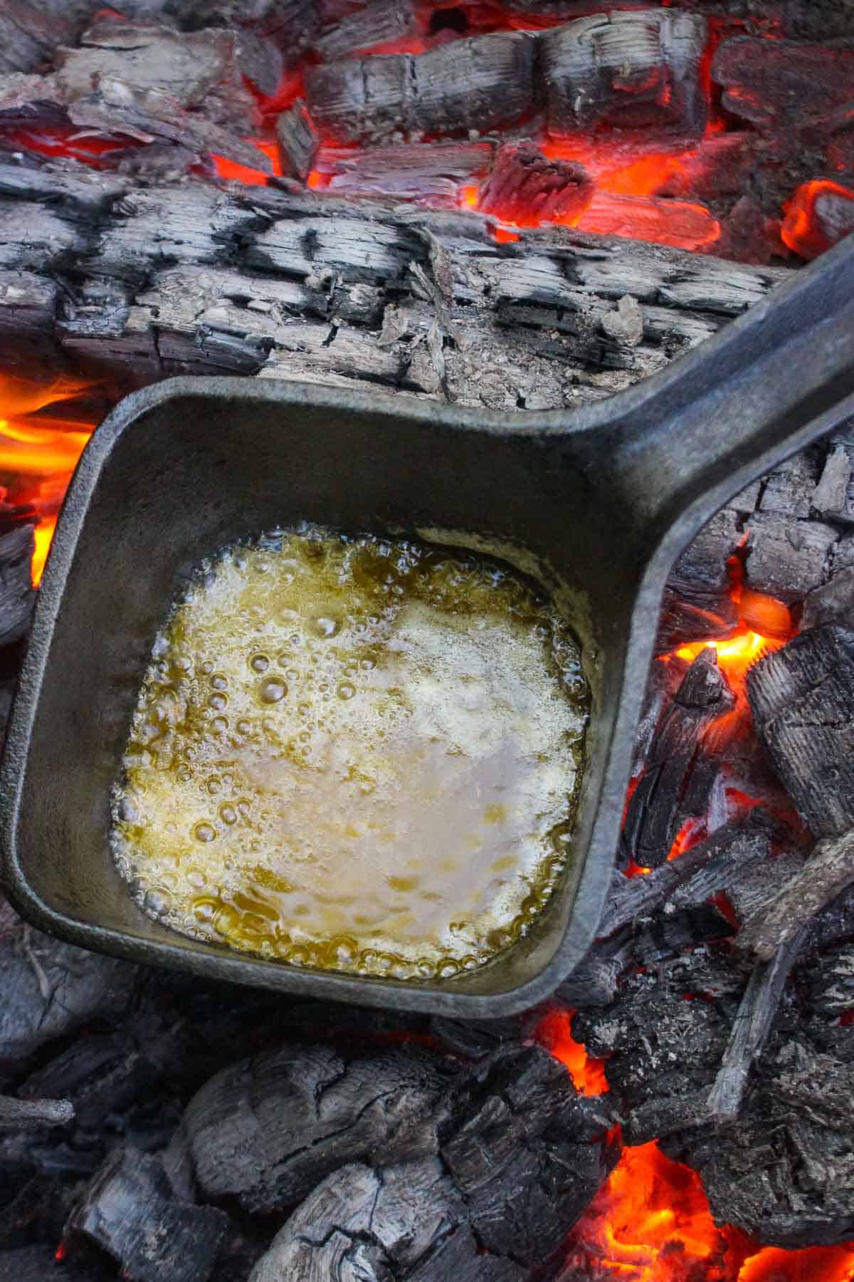 The butter sauce boiling while sitting the coals. 