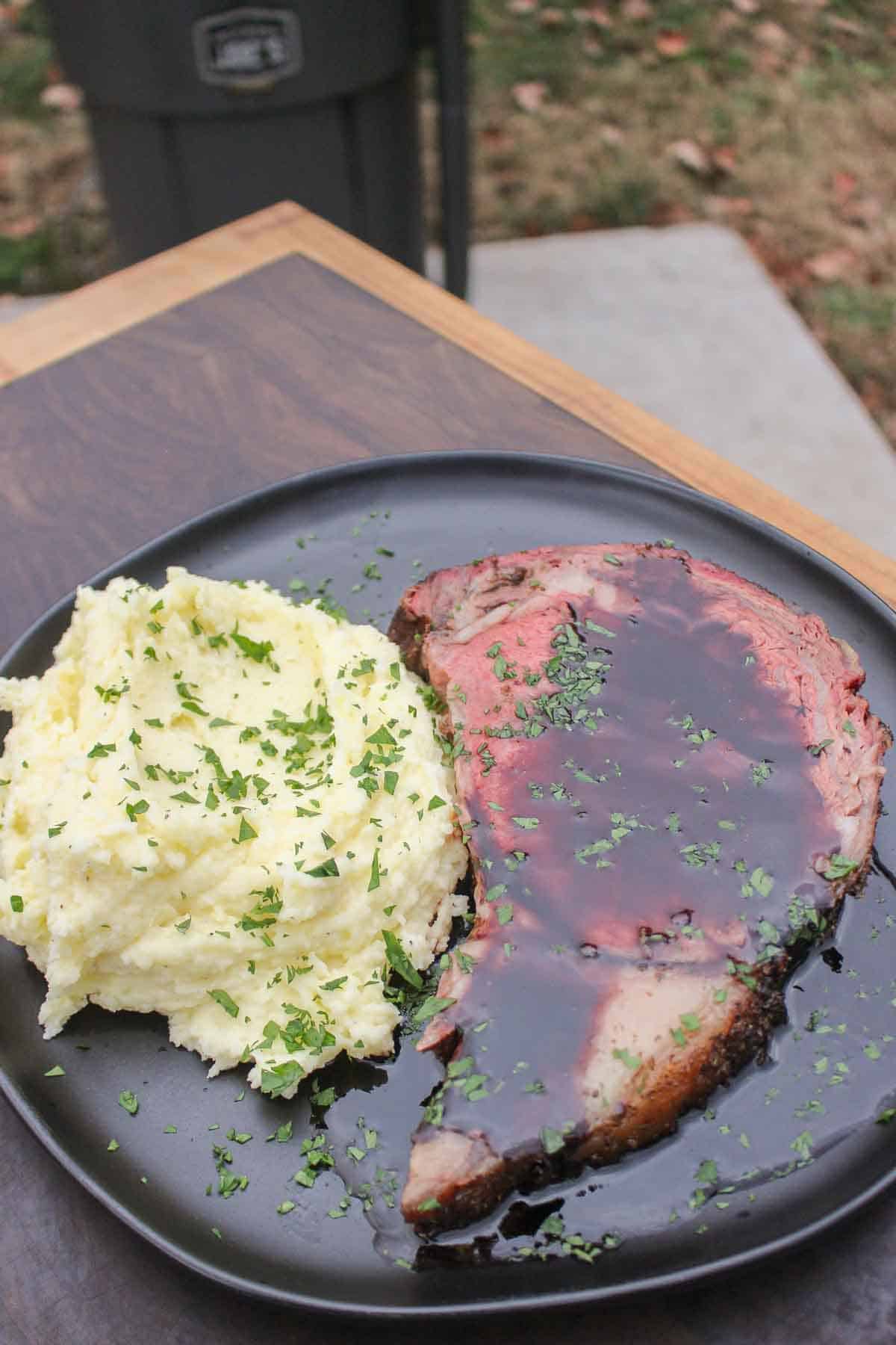 The juicy prime rib is served with mashed potatoes and a red wine sauce, and sprinkled with fresh chopped parsley. 