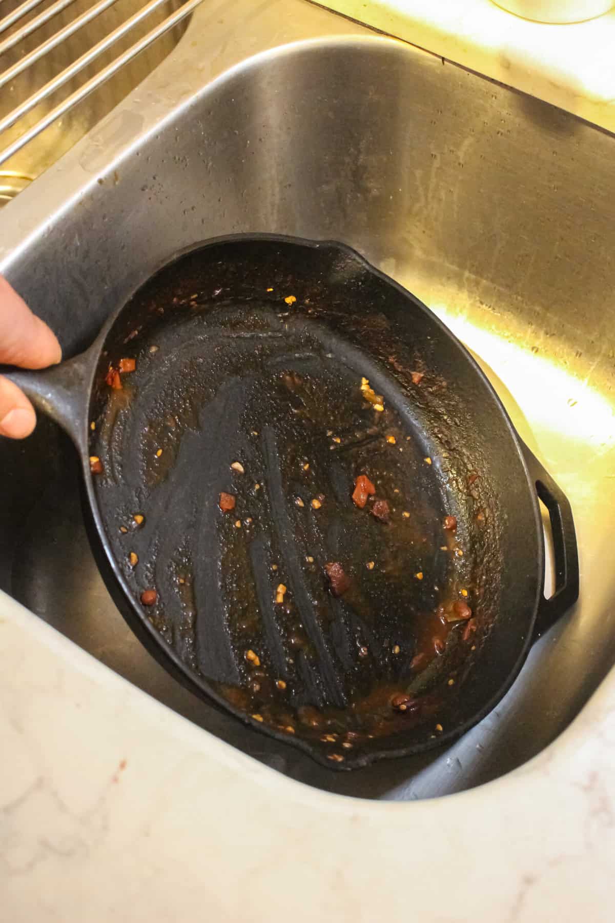 A dirty cast iron pan with stuck food bits on it.