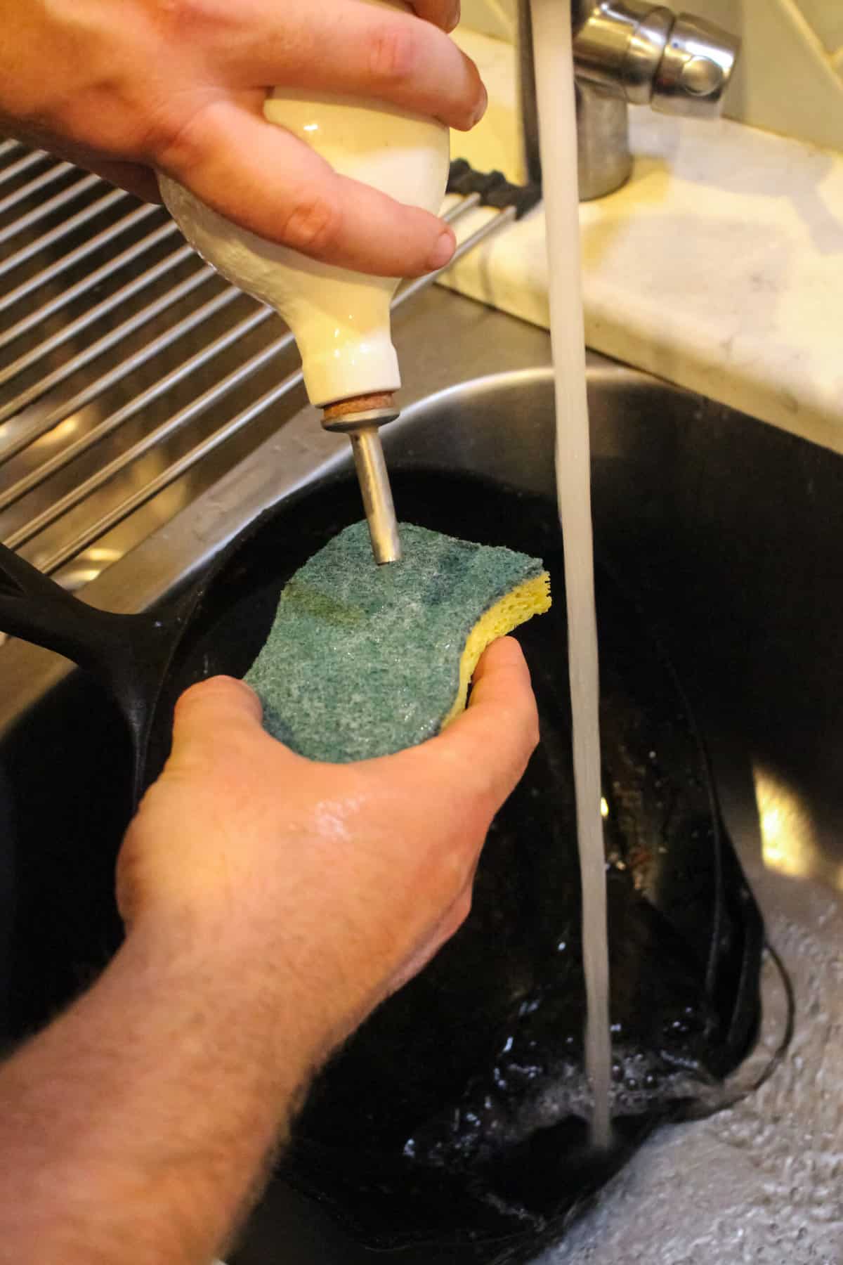 Adding a little soup to a sponge to clean the cast iron skillet.