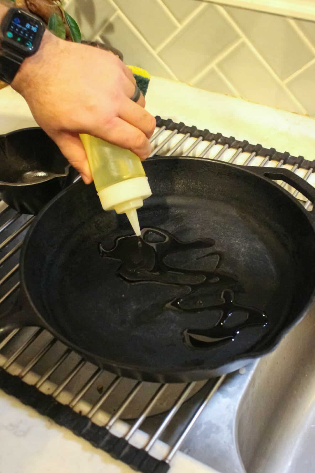 Adding oil to the clean cast iron pan.