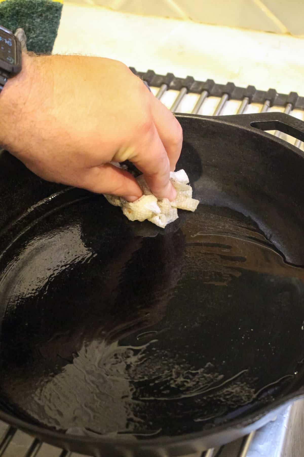 Wiping the oil around the cast iron pan to re-season it.