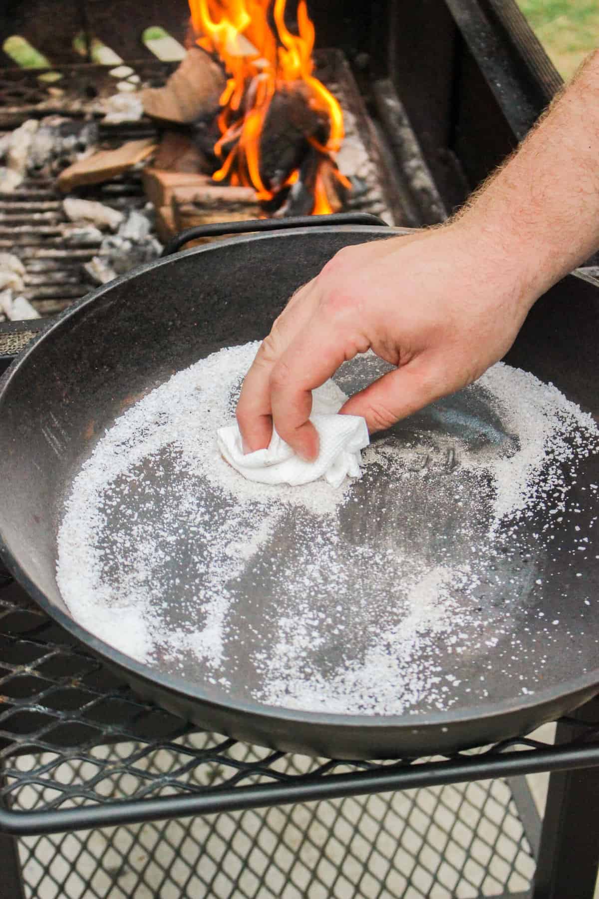 Cleaning the cast iron skillet by rubbing it with salt and a paper towel.