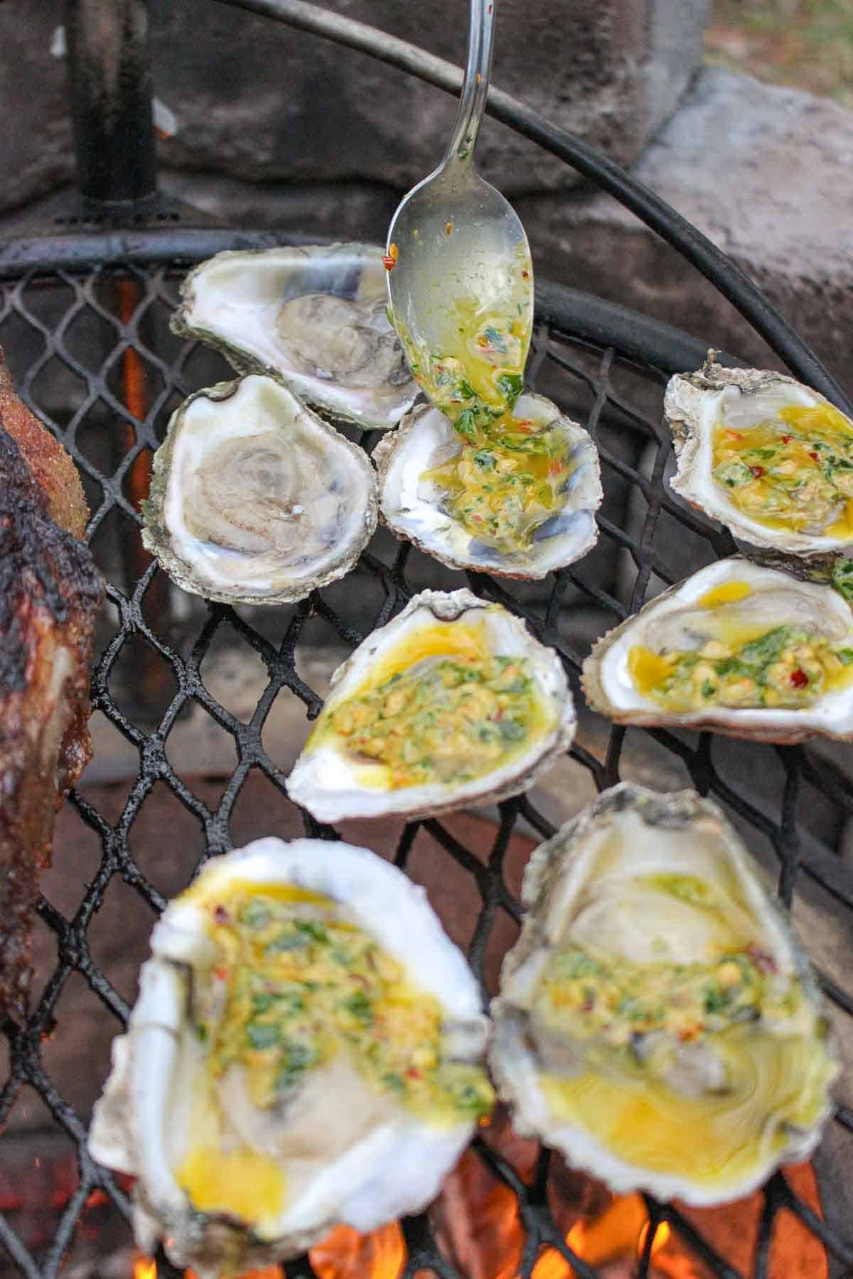 Drizzling the spicy butter over the shucked oysters. 