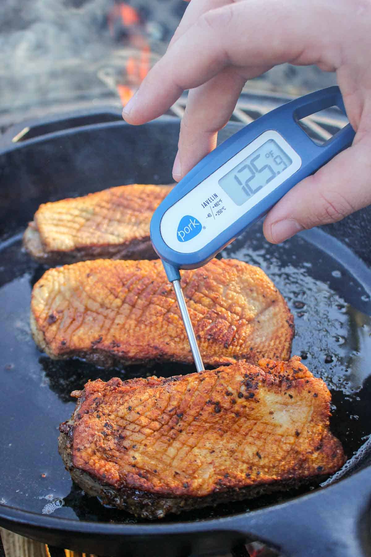 A digital thermometer is used to check the internal temperature of the duck, aiming for 130 degrees F. 