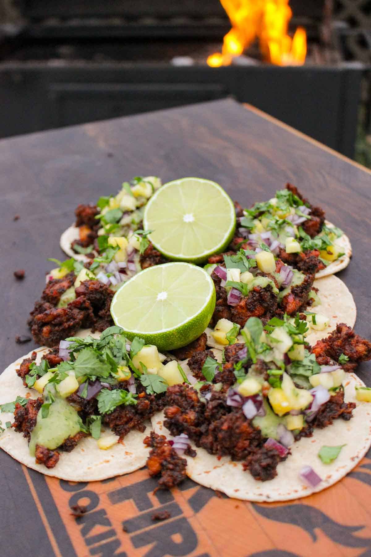 The tacos are laid out on a cutting board and served with slices of lime. 