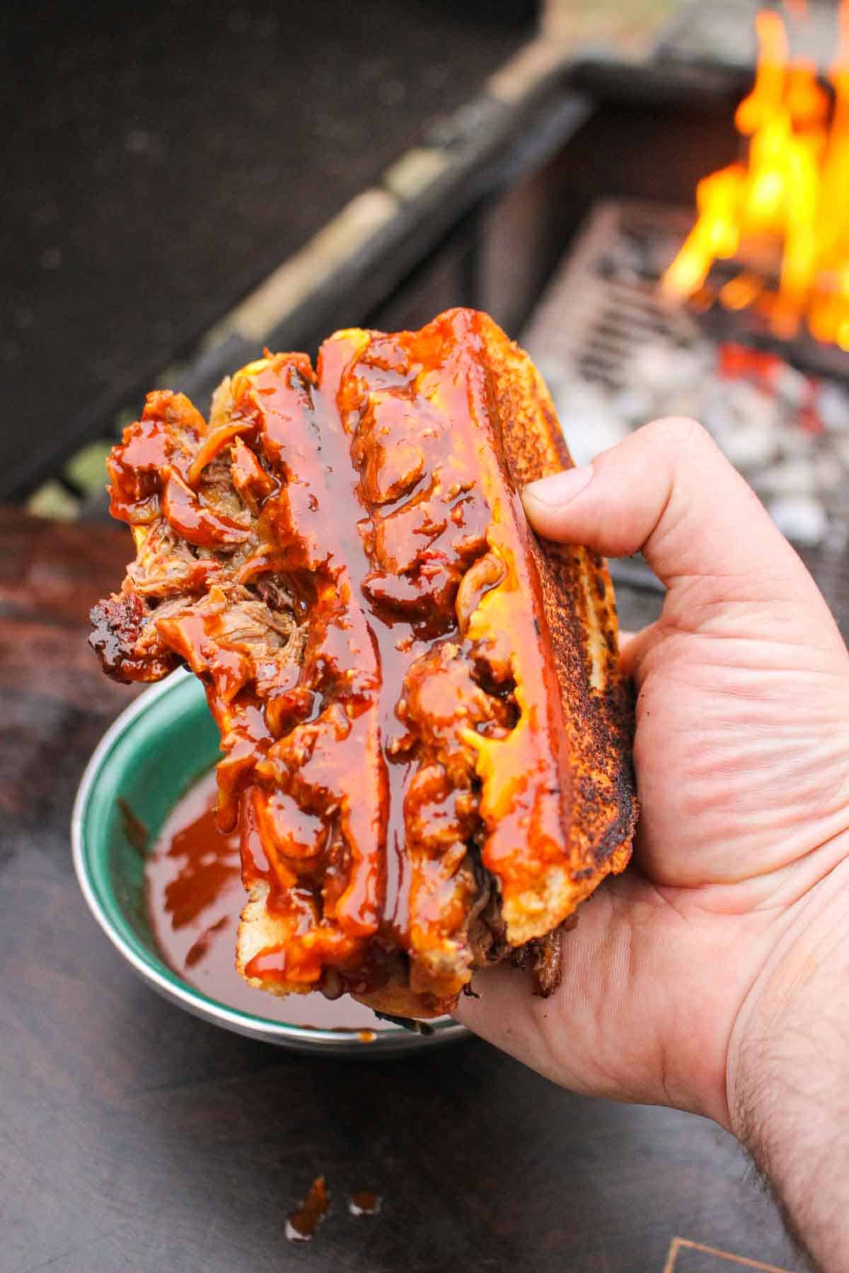 The sandwich is dipped in BBQ sauce. 