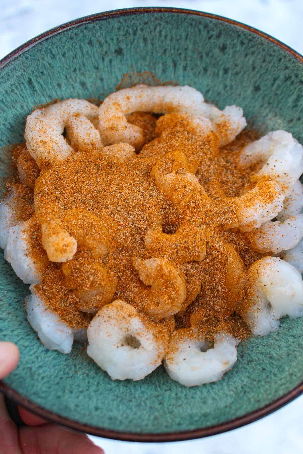 The shrimp are seasoned in a bowl. 