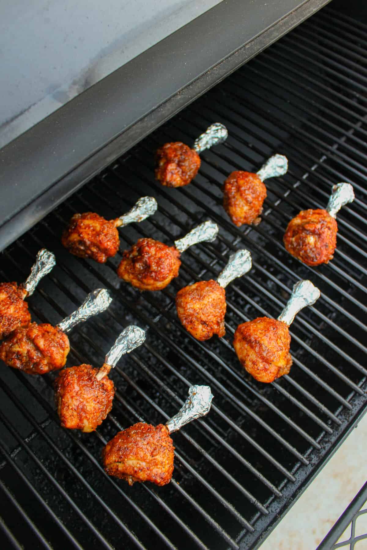 Some chicken lollipops sitting on the smoker.