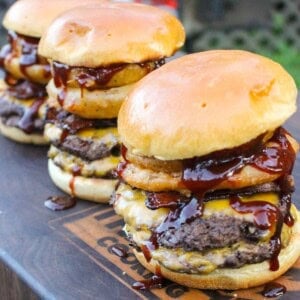 BBQ bacon burgers fully assembled with onion rings.