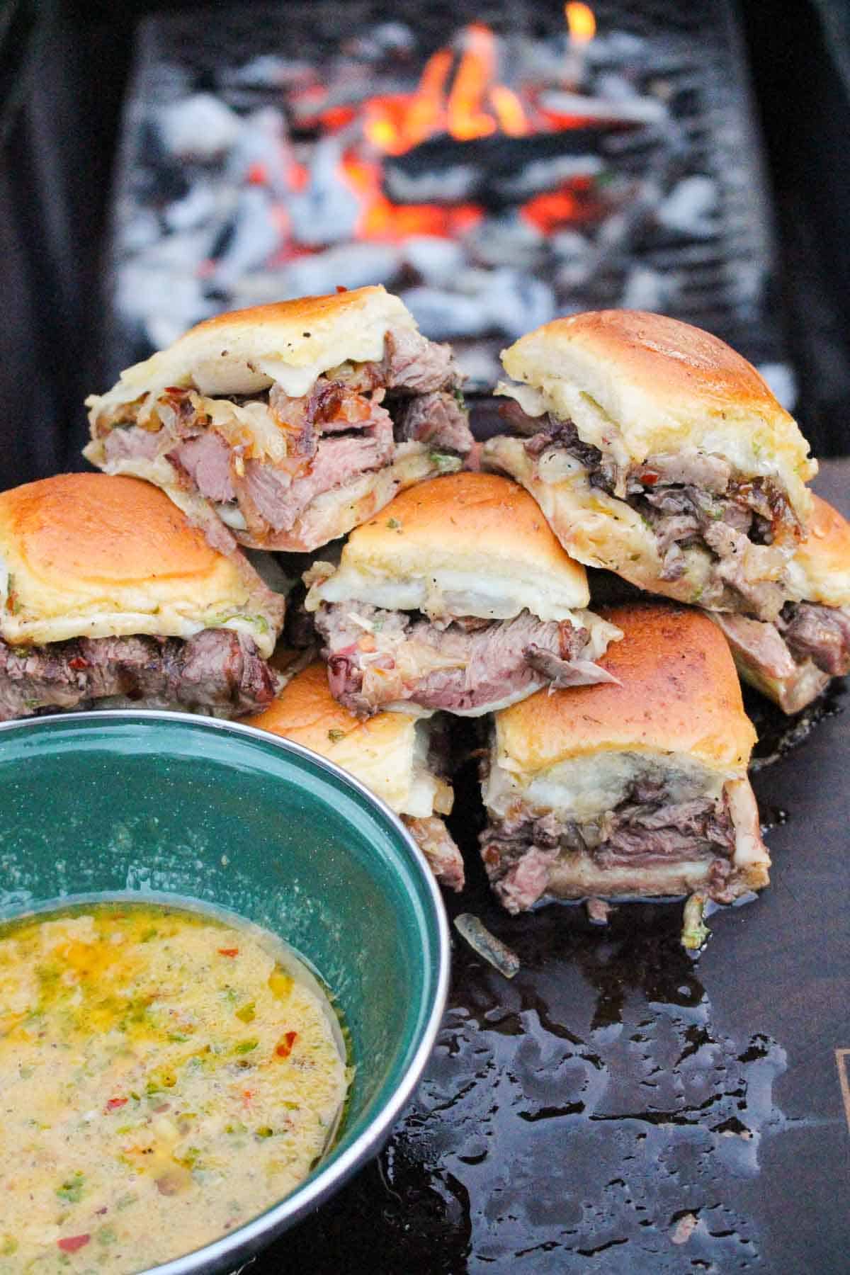 Cowboy Butter Sliders sitting in a pile next to the dipping sauce. 